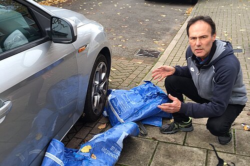 Paul Lorber pointing at a blown away blue recycling bag