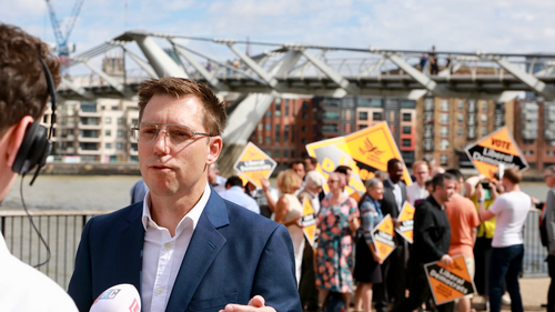 Rob Blackie pictured with a microphone on a bridge with Liberal Democrat activists